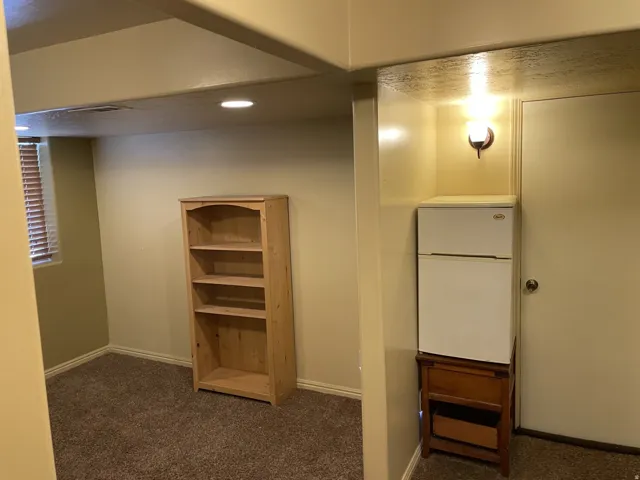 Recessed ceiling lighting, textured carpeting, window with horizontal blinds, and a built-in wall sconce