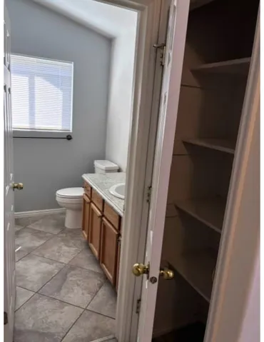 Bathroom featuring a wood-finish vanity with a countertop, integrated sink, and tiled flooring