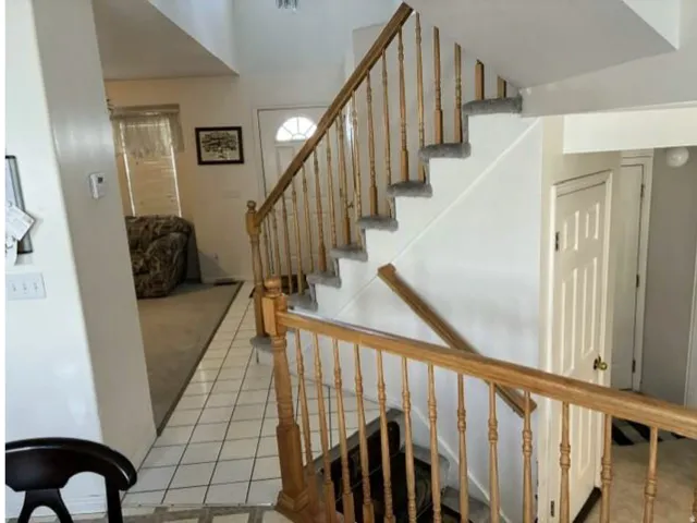 Two-story entryway featuring wood-finish banisters and railings, a white paneled door, and tile flooring