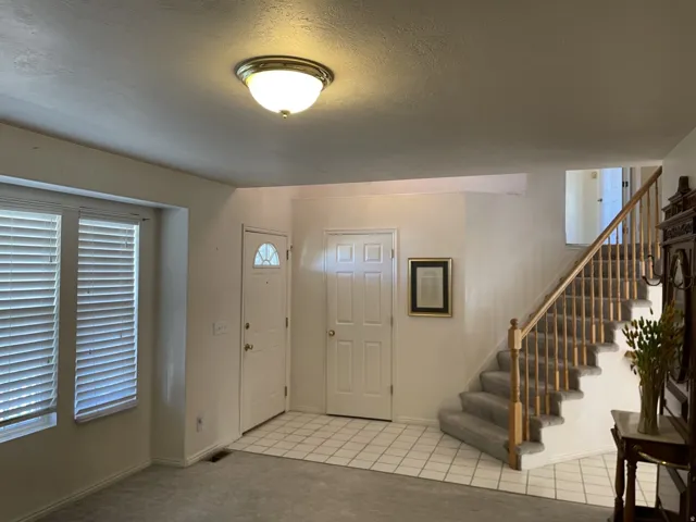 Entryway featuring a staircase with wood balusters, tiled flooring, and a flush mount ceiling light