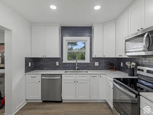 Home 2/2 - 938 E Herbert Avenue --Modern kitchen featuring white shaker-style cabinetry, a dark subway tile backsplash, light-toned countertops, stainless steel appliances, and recessed lighting