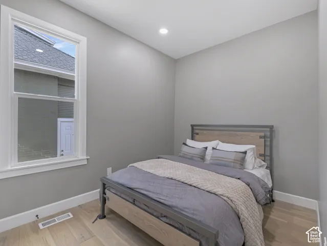 Home 1/2 -- 1046 S Lincoln Street -- Light-filled bedroom featuring wood-finish flooring, a white trim window, neutral wall paint, recessed ceiling lighting, and crisp white baseboards