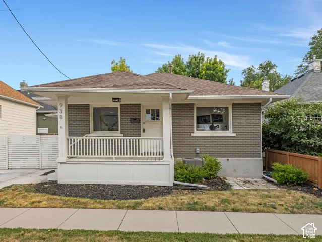 Home 2/2 - 938 E Herbert Avenue -- Traditional bungalow exterior featuring gray brick siding, a covered front porch with white railing, a brown shingle roof, and established landscaping