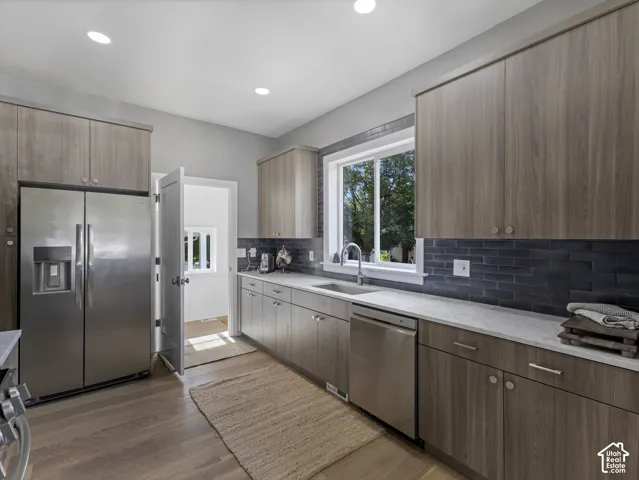 Home 1/2 -- 1046 S Lincoln Street -- Modern kitchen featuring wood-finish cabinetry, stainless steel appliances, and a dark subway tile backsplash