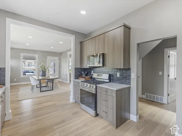 Home 1/2 -- 1046 S Lincoln Street -- Kitchen area featuring wood-finish cabinetry, stainless steel range with overhead microwave, and a dark tile backsplash