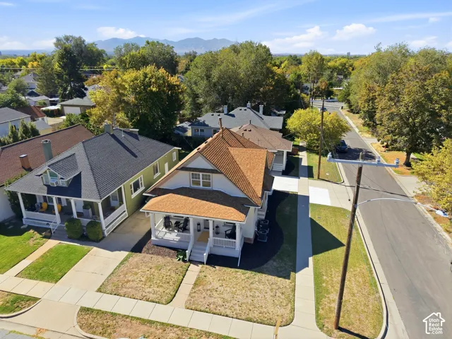 Home 1/2 -- 1046 S Lincoln Street -- Aerial perspective featuring a Craftsman-style residence with an expansive front porch, gabled roofline, and mountain backdrop