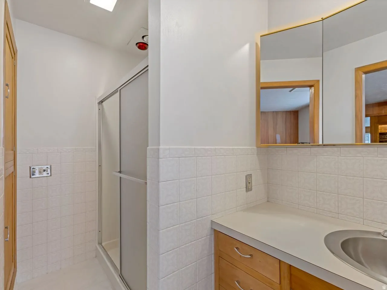 Bathroom vanity with a built-in sink, wood-finish cabinetry, and an illuminated medicine cabinet
