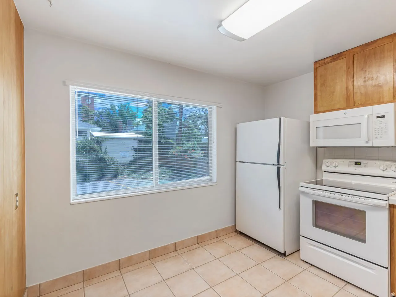 Kitchen featuring wood-finish cabinetry, a white refrigerator, and a white electric range with an overhead microwave