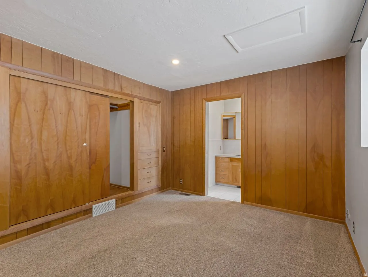 Wood-paneled room featuring built-in sliding closet doors with integrated drawers and wall paneling