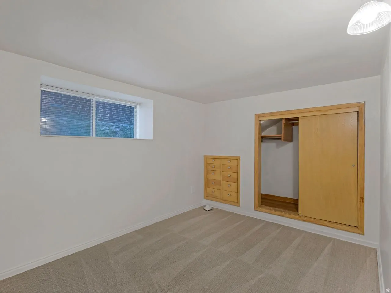 Carpeted room featuring a double-paned window, built-in wooden dresser, and a closet with a sliding wood door