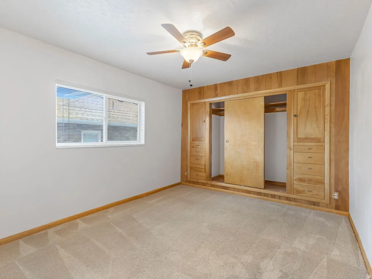 Bedroom featuring built-in wood-paneled cabinetry with sliding closet doors and integrated drawers