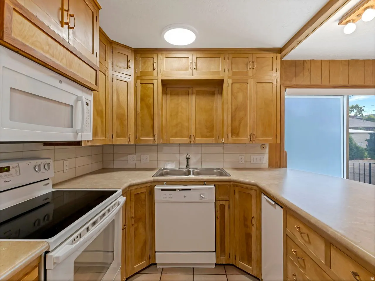 Kitchen featuring abundant wood cabinetry, light countertops, and a tile backsplash