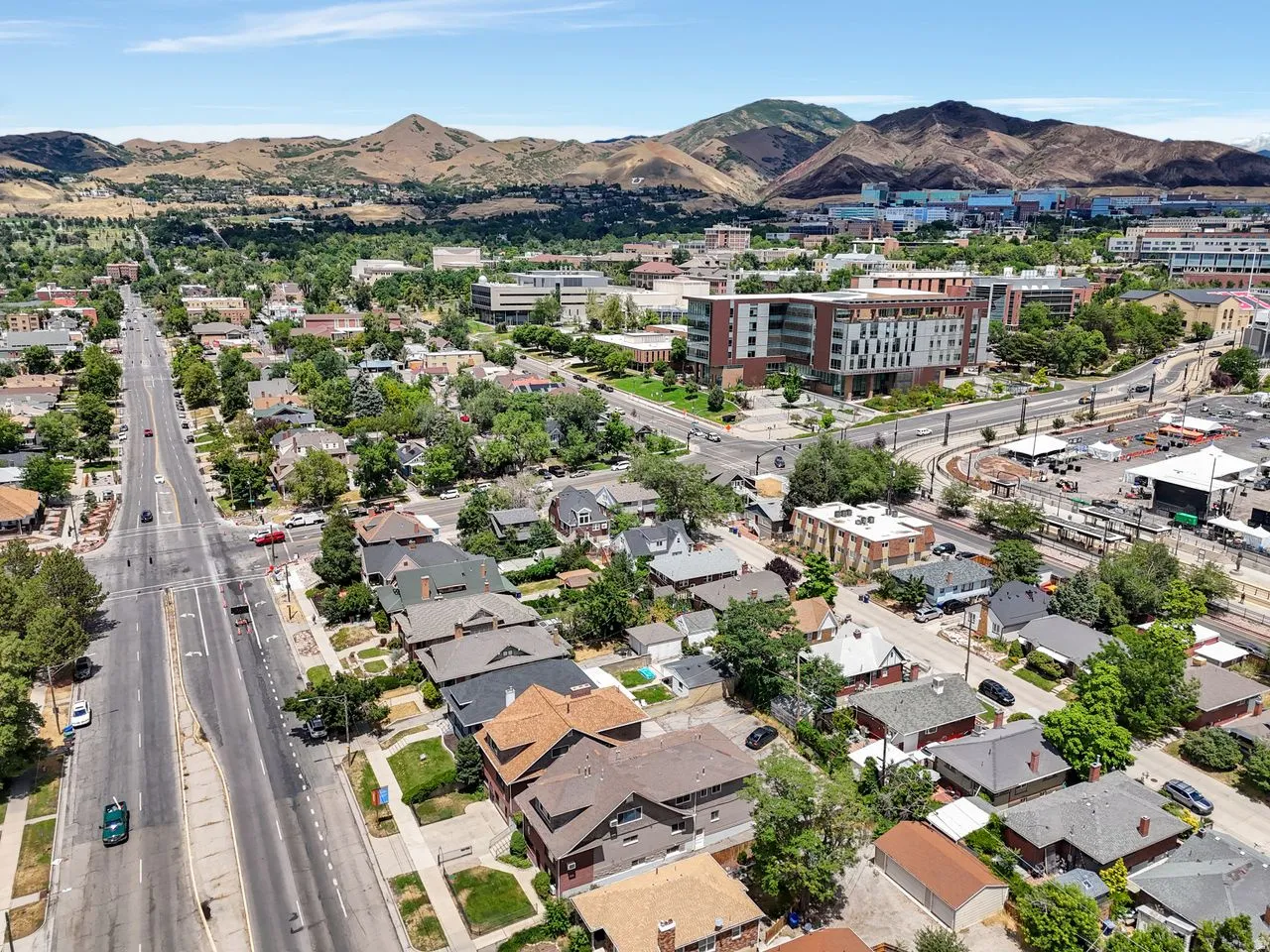 Aerial perspective showcasing a residential neighborhood with tree-lined streets, surrounded by prominent mountain ranges