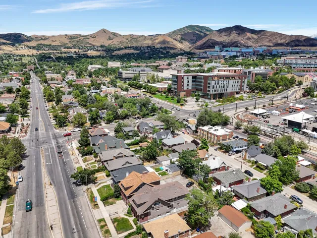 Aerial perspective showcasing a residential neighborhood with tree-lined streets, surrounded by prominent mountain ranges