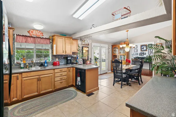 Kitchen featuring light wood cabinetry, a mosaic tile backsplash, and a double basin stainless steel sink