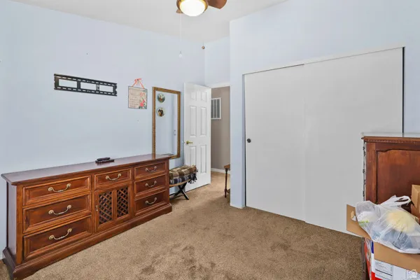 Carpeted room with a ceiling fan light fixture and a two-panel sliding closet