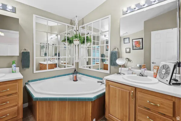 Bathroom featuring a corner soaking tub with teal tile surround