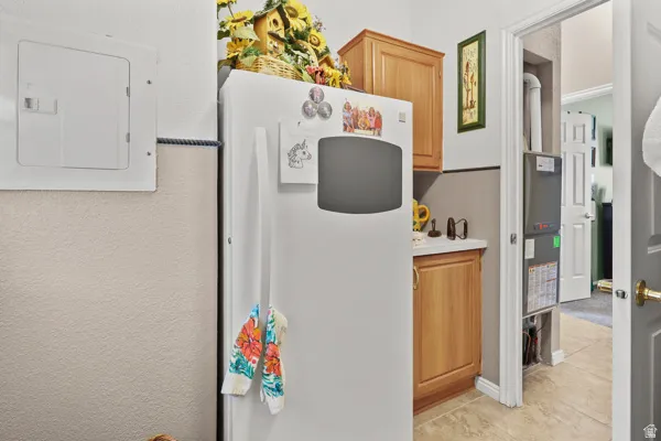 White refrigerator alongside wood cabinetry and a light-toned countertop