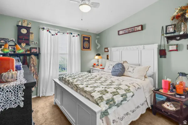 Spacious bedroom featuring light green walls, a white paneled headboard, a ceiling fan with integrated lighting, and carpet flooring