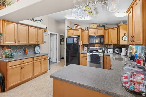 Kitchen featuring light wood-finish cabinetry, dark countertops, and a tiled backsplash