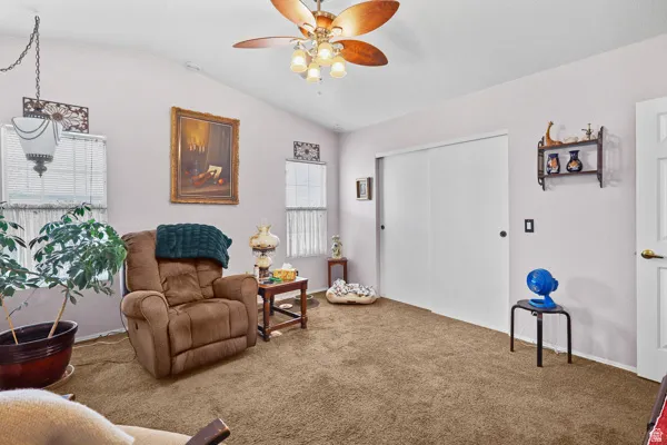 Carpeted interior space featuring a vaulted ceiling with a ceiling fan