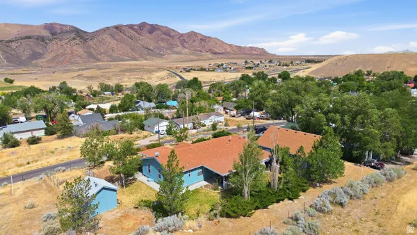 Single-story residence with a brown shingle roof and light blue siding, set against a mountainous backdrop