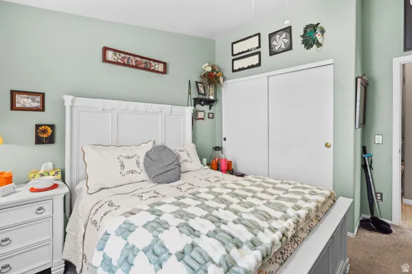 Interior space featuring a white paneled headboard and footboard, light green wall paint, and white sliding closet doors