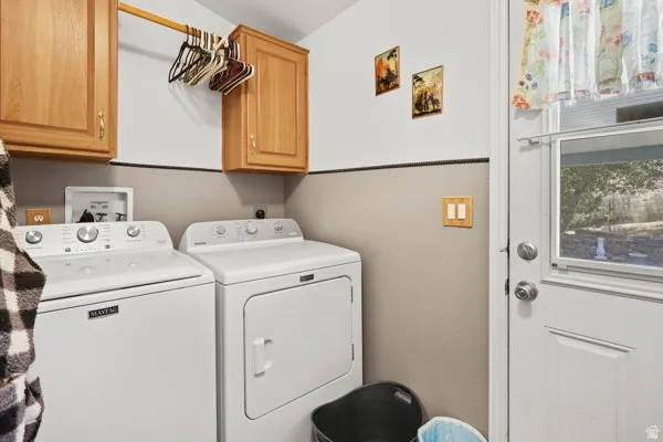 Dedicated laundry area featuring white appliances, a wooden hanging rod, and upper cabinetry