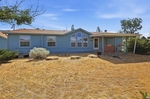 Rear exterior featuring a covered patio, multiple windows, and a light blue facade