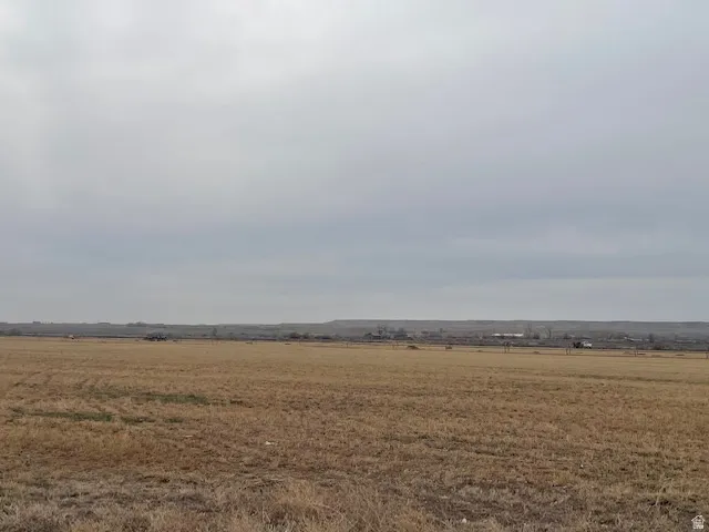 Expansive rural landscape featuring a broad, level field of dry grass
