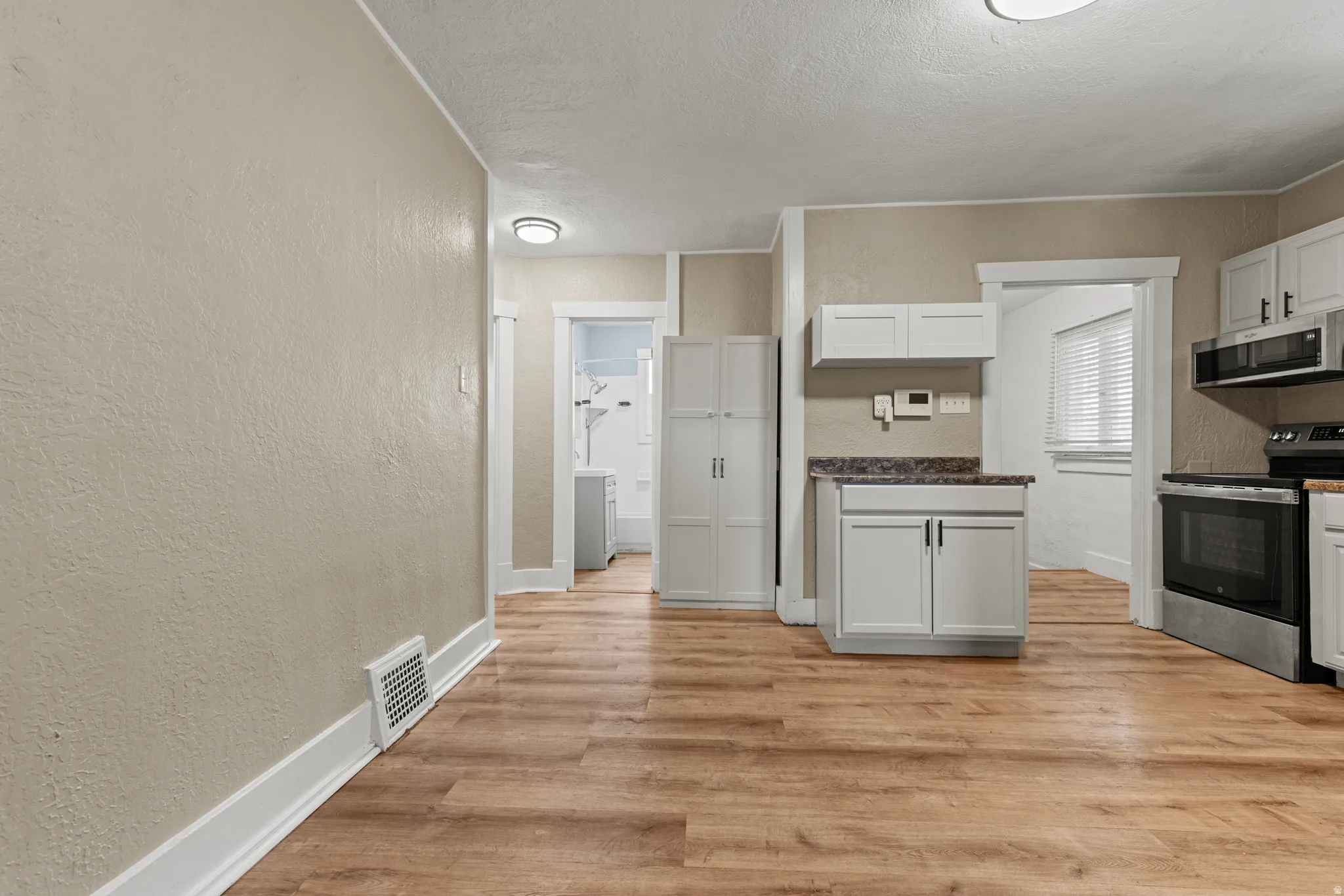 Open-concept room featuring wood-finish flooring, light-colored walls, white baseboards, and ceiling-mounted lighting