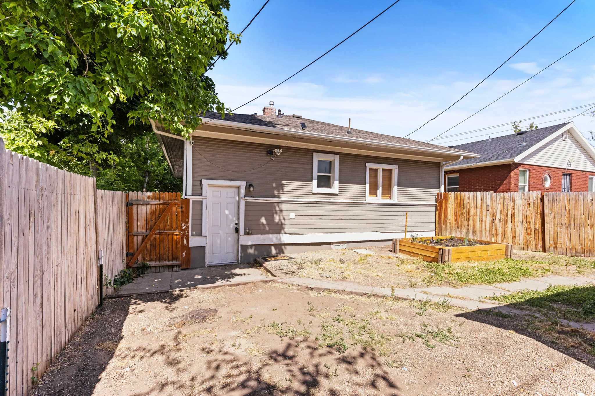 Rear exterior of the property featuring horizontal siding, a private wood fence, and a raised garden bed
