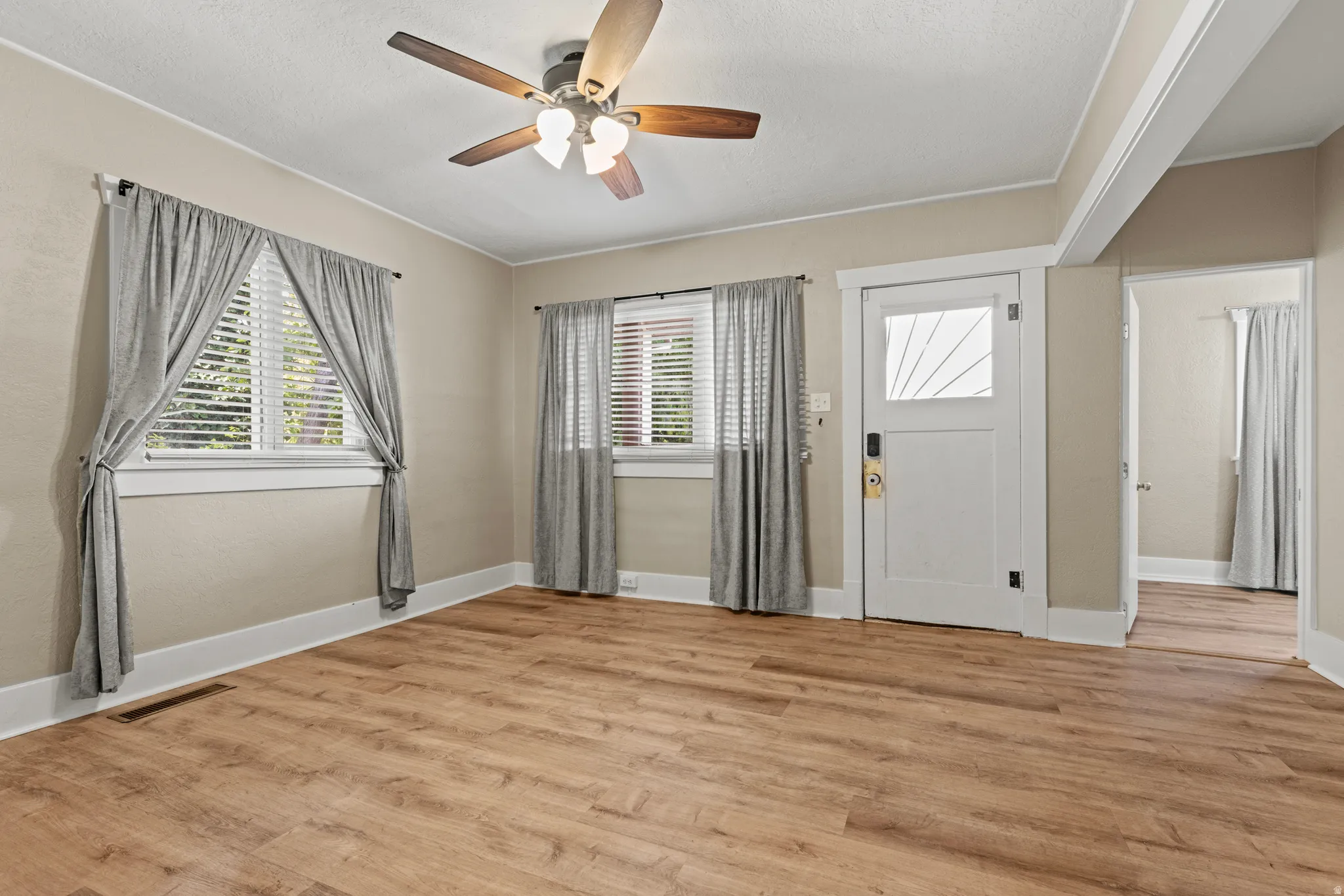 Spacious room featuring wood-finish flooring, light-toned wall paint, and white trim throughout