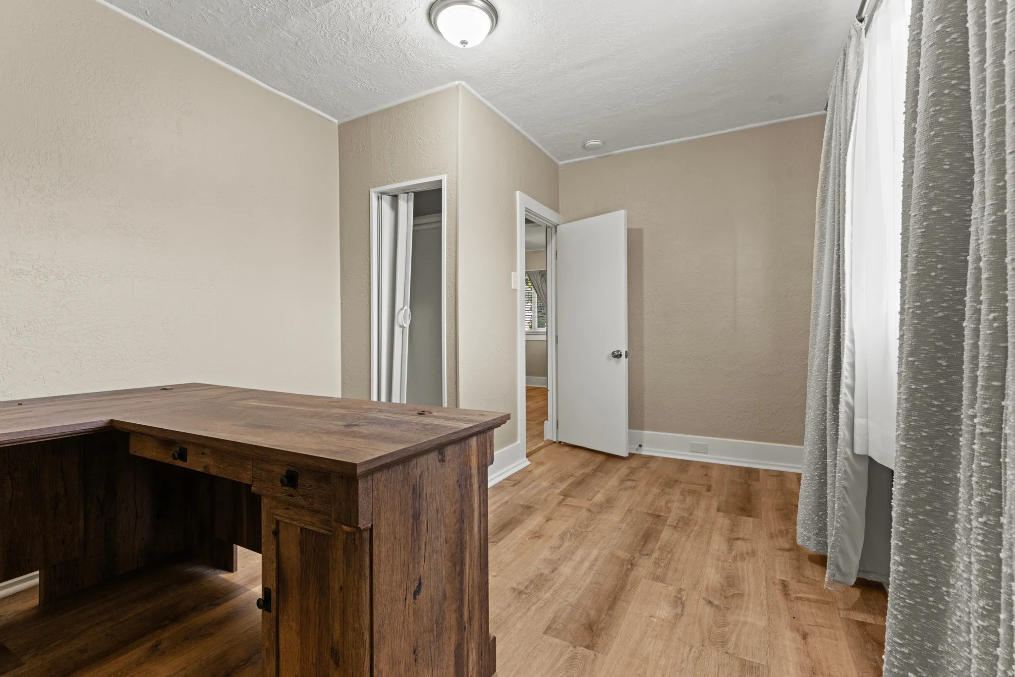 Room with wood-finish flooring, neutral wall paint, and white baseboards
