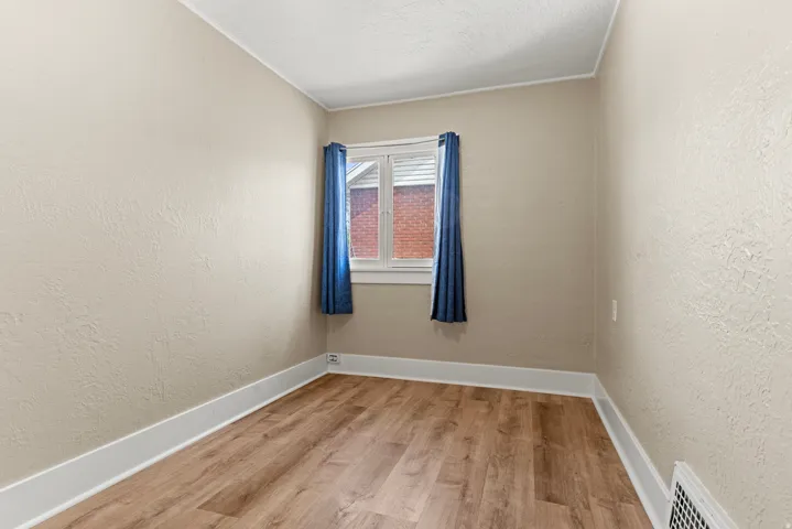 Neutral-toned room with wood-finish flooring, white baseboards, and textured walls