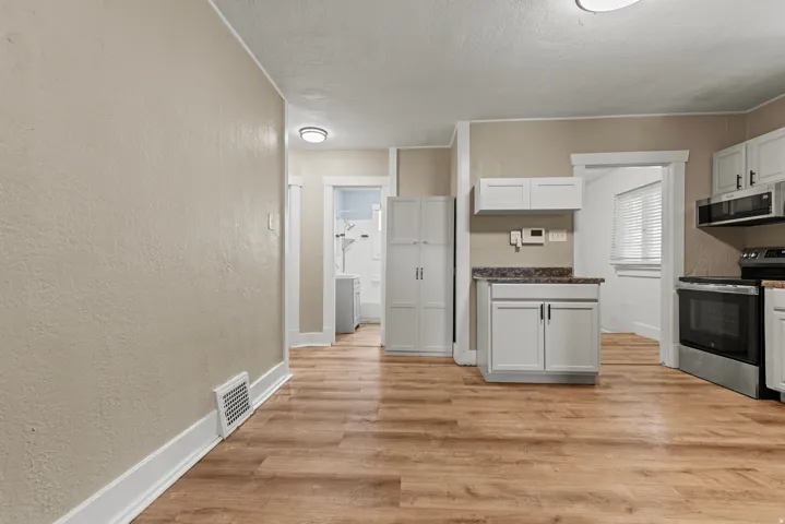 Open-concept room featuring wood-finish flooring, light-colored walls, white baseboards, and ceiling-mounted lighting