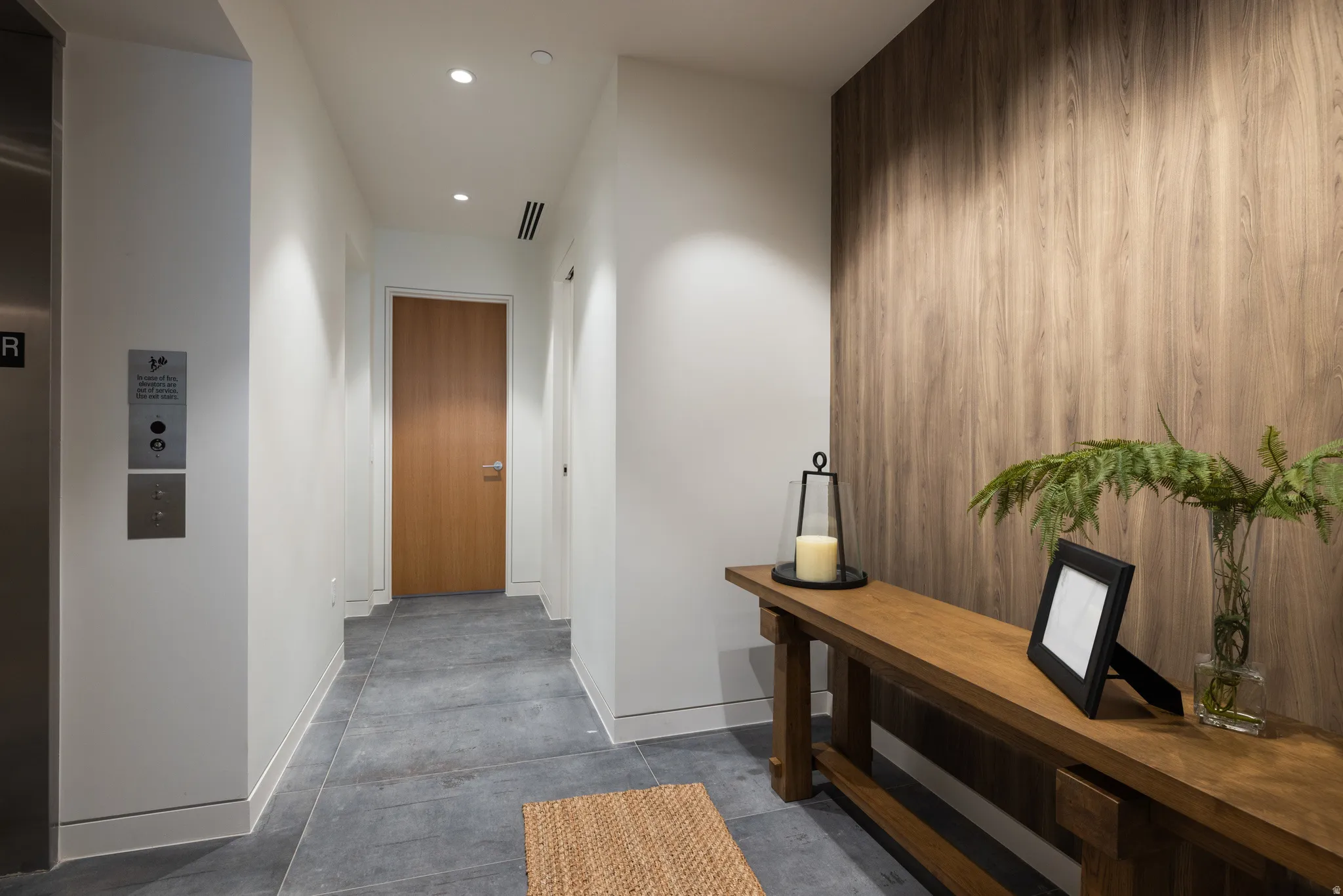 Entryway featuring a wood-panel accent wall, recessed lighting, and large format tile flooring