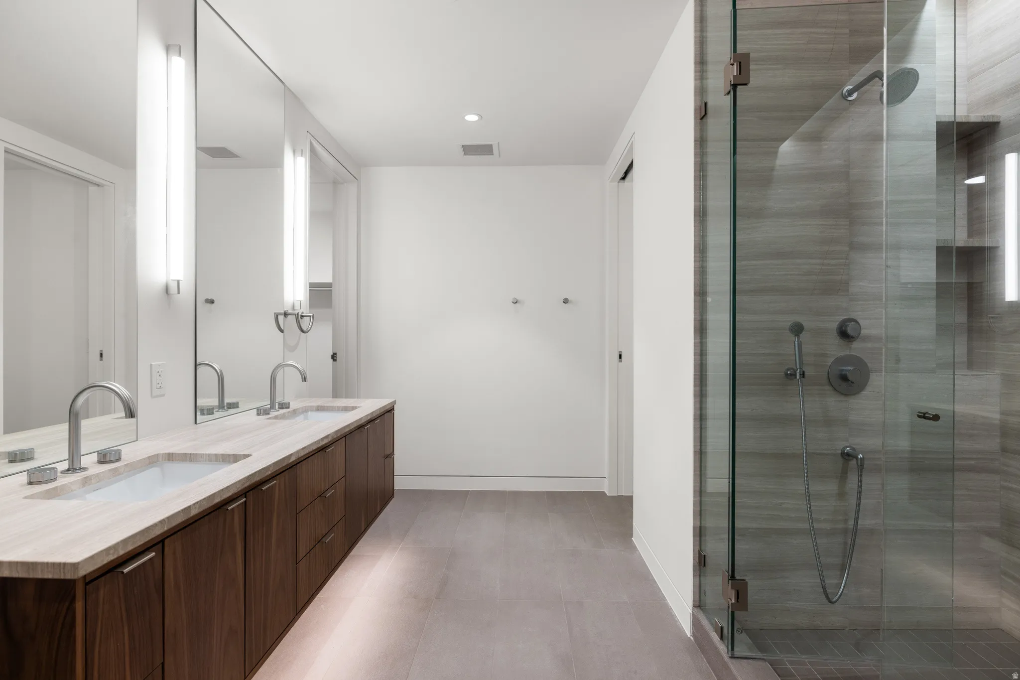 Modern bathroom featuring a dual vanity with a light-toned countertop, under-cabinet lighting, and a full-length mirror
