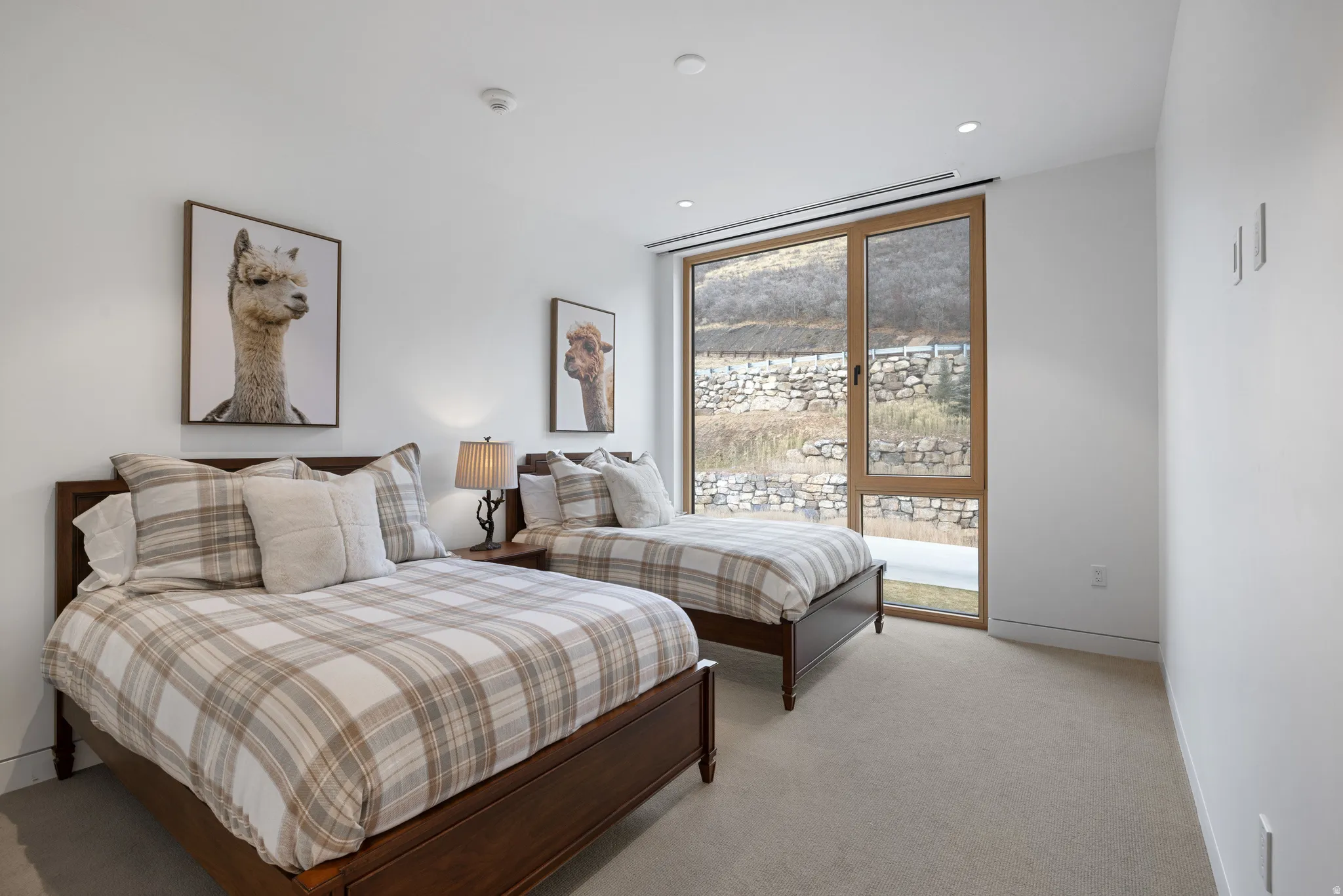 Room featuring two wood-frame beds, soft neutral carpeting, and white walls
