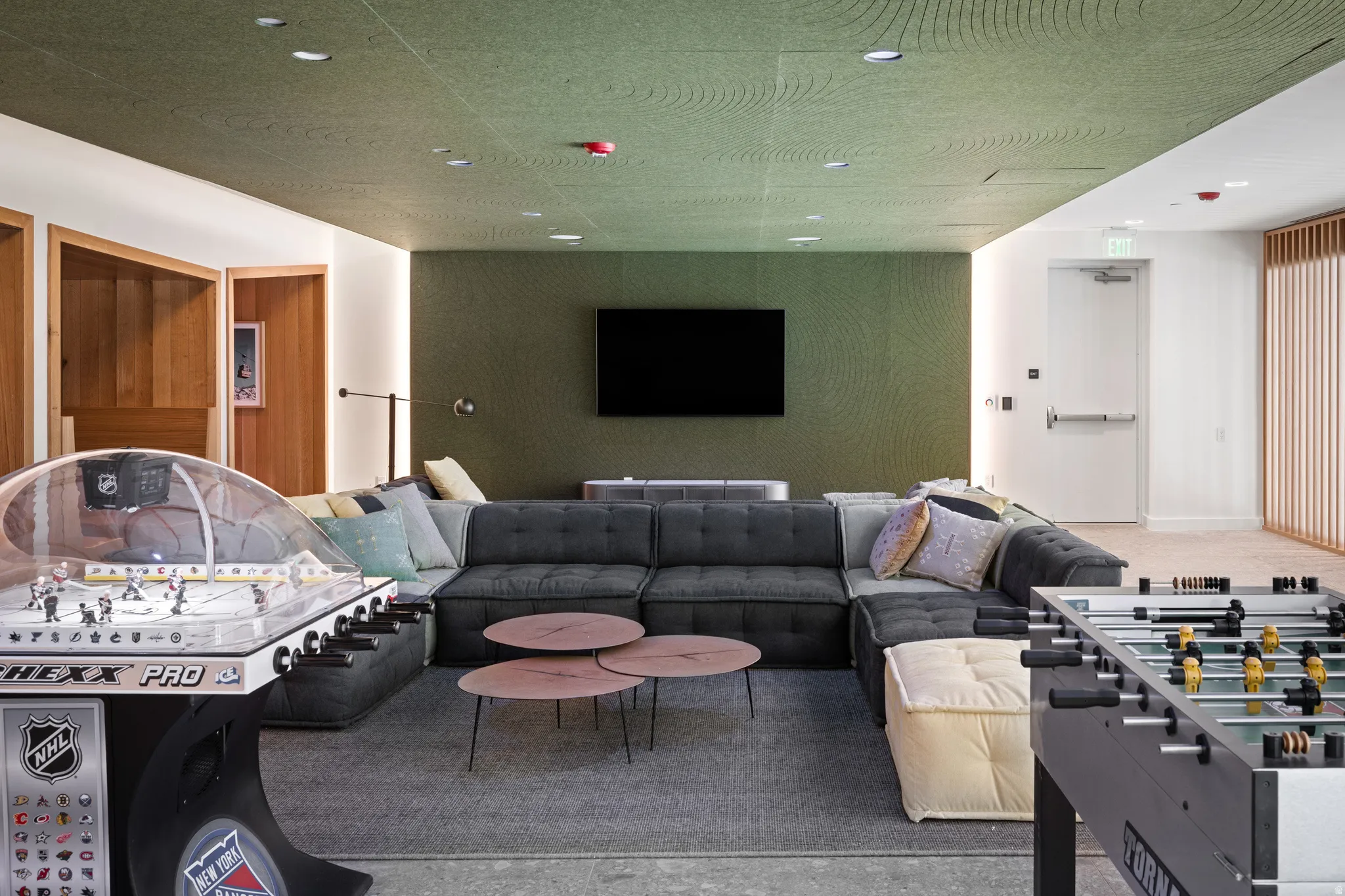 Spacious entertainment area featuring a large sectional sofa, recessed lighting, accent wall, wood-paneled alcoves, and a textured green ceiling