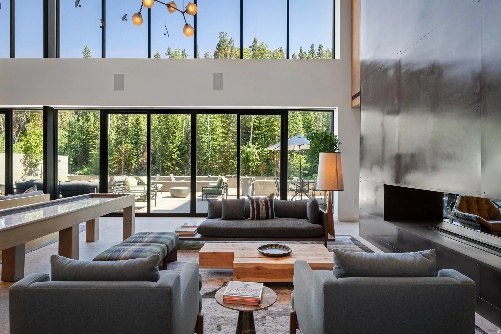 Great room featuring a full-height metal-clad fireplace, soaring ceilings with clerestory windows, and a built-in shuffleboard table