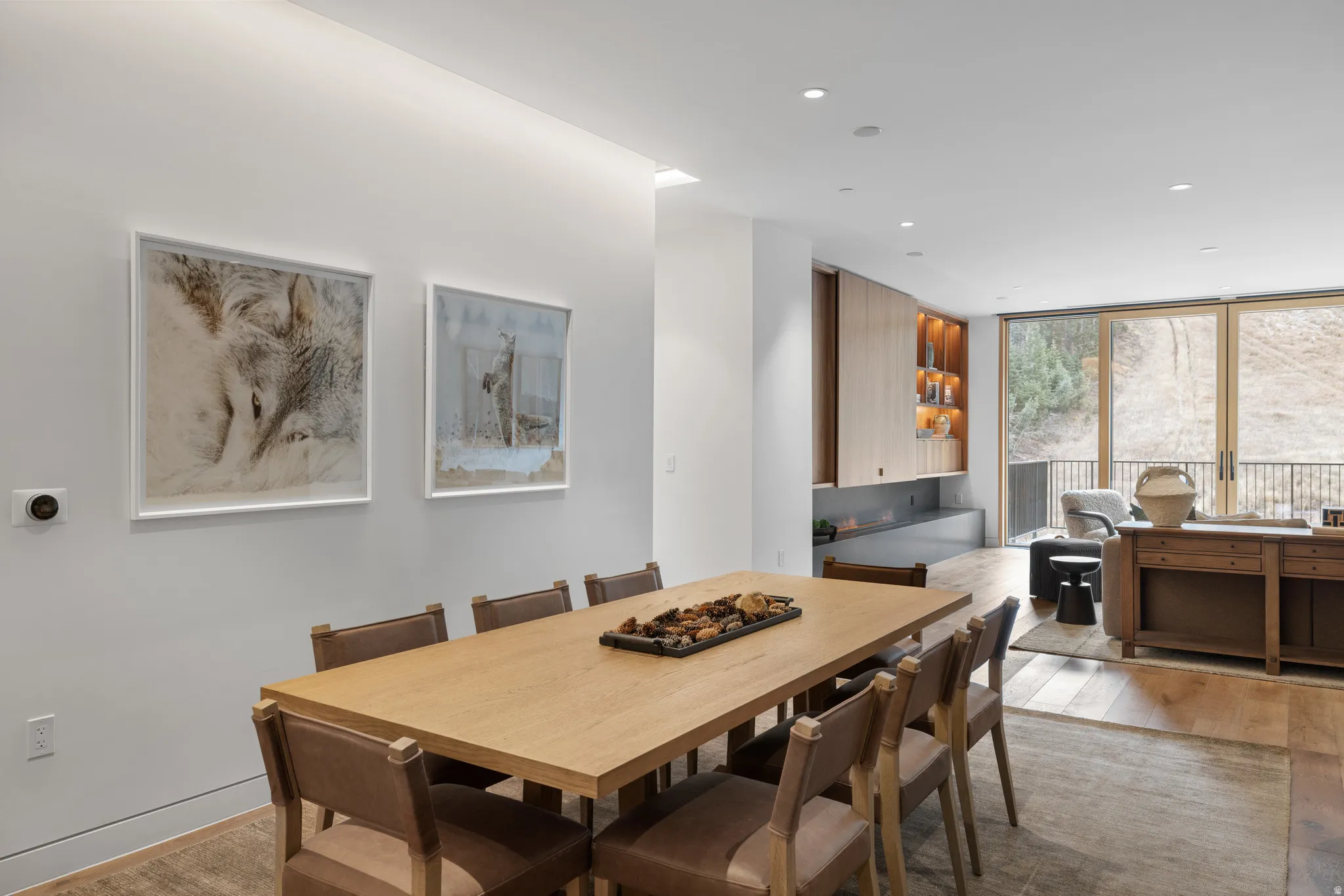 Open-concept dining area featuring wood-finish flooring, recessed lighting, and a modern built-in fireplace with integrated shelving