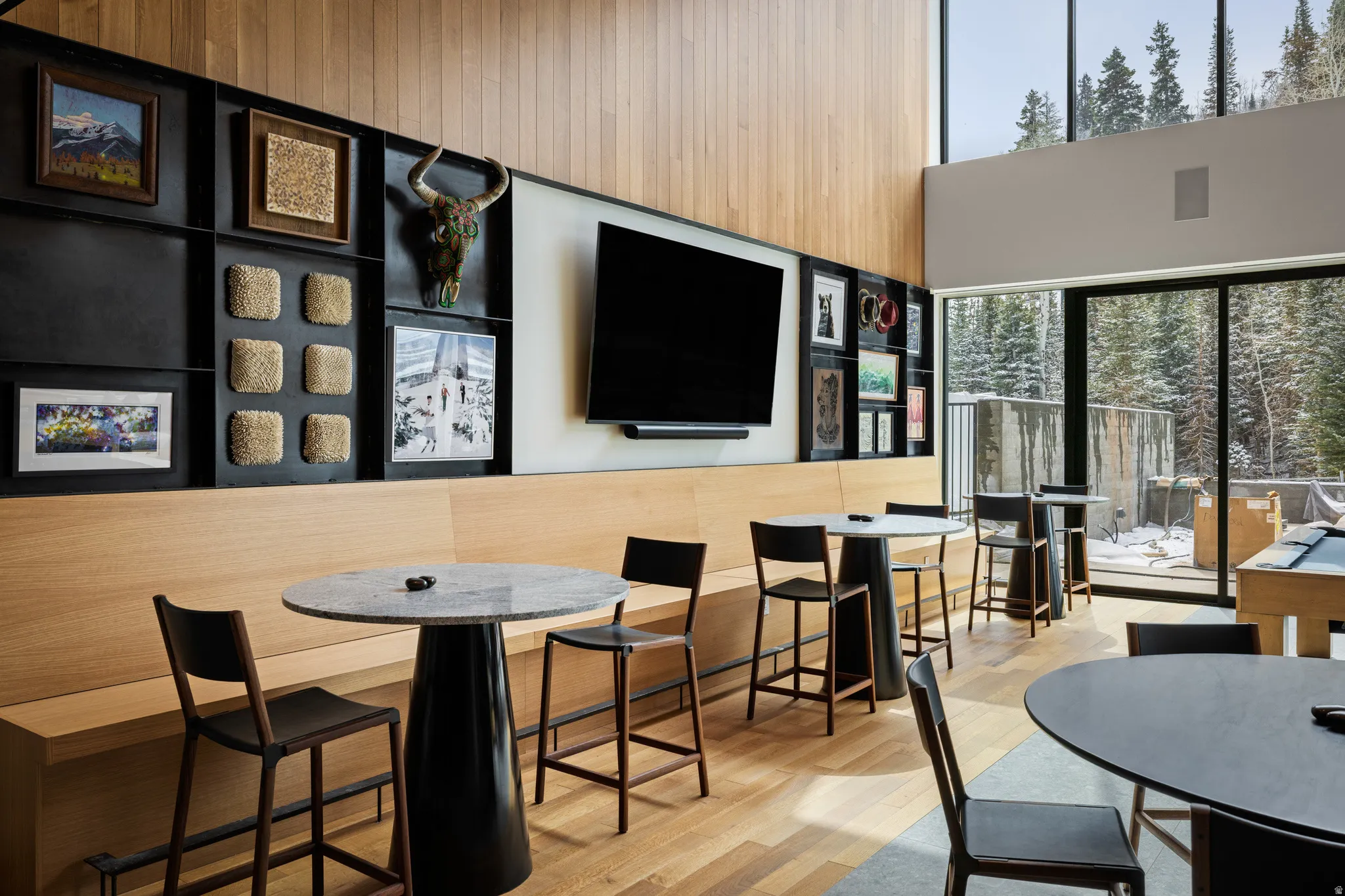 Spacious entertainment area featuring wood-finish flooring, a built-in bench, and a wall-mounted display