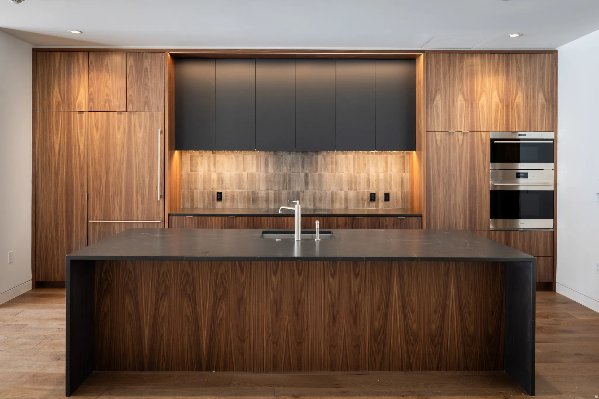 Full kitchen featuring dark wood-finish cabinetry, integrated refrigerator, and stainless-steel double ovens