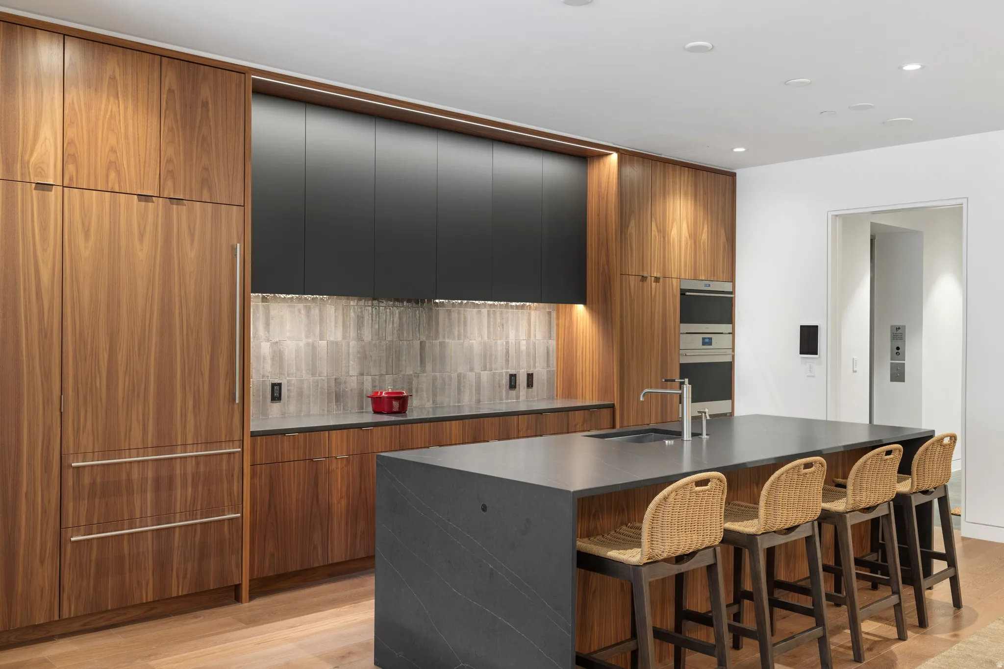 Modern kitchen featuring wood-finish cabinetry, integrated refrigerator, and a large center island with a sink