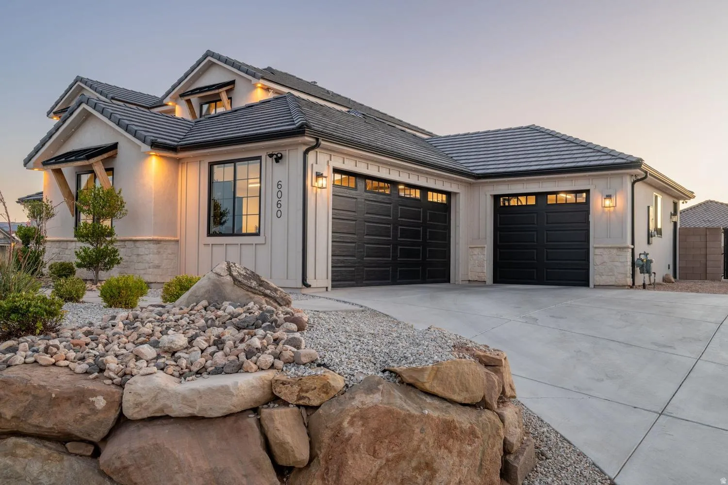 Modern farmhouse exterior featuring board and batten siding, stone accents, and a dark tile roof