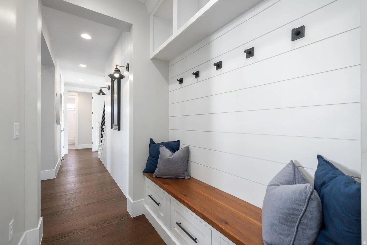 Built-in bench with a rich wood-finish top and white cabinetry featuring dark hardware