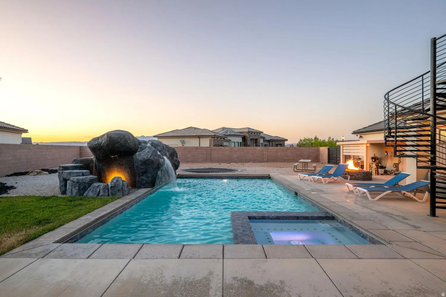 Inviting backyard oasis featuring a rectangular swimming pool with integrated spa and rock waterfall