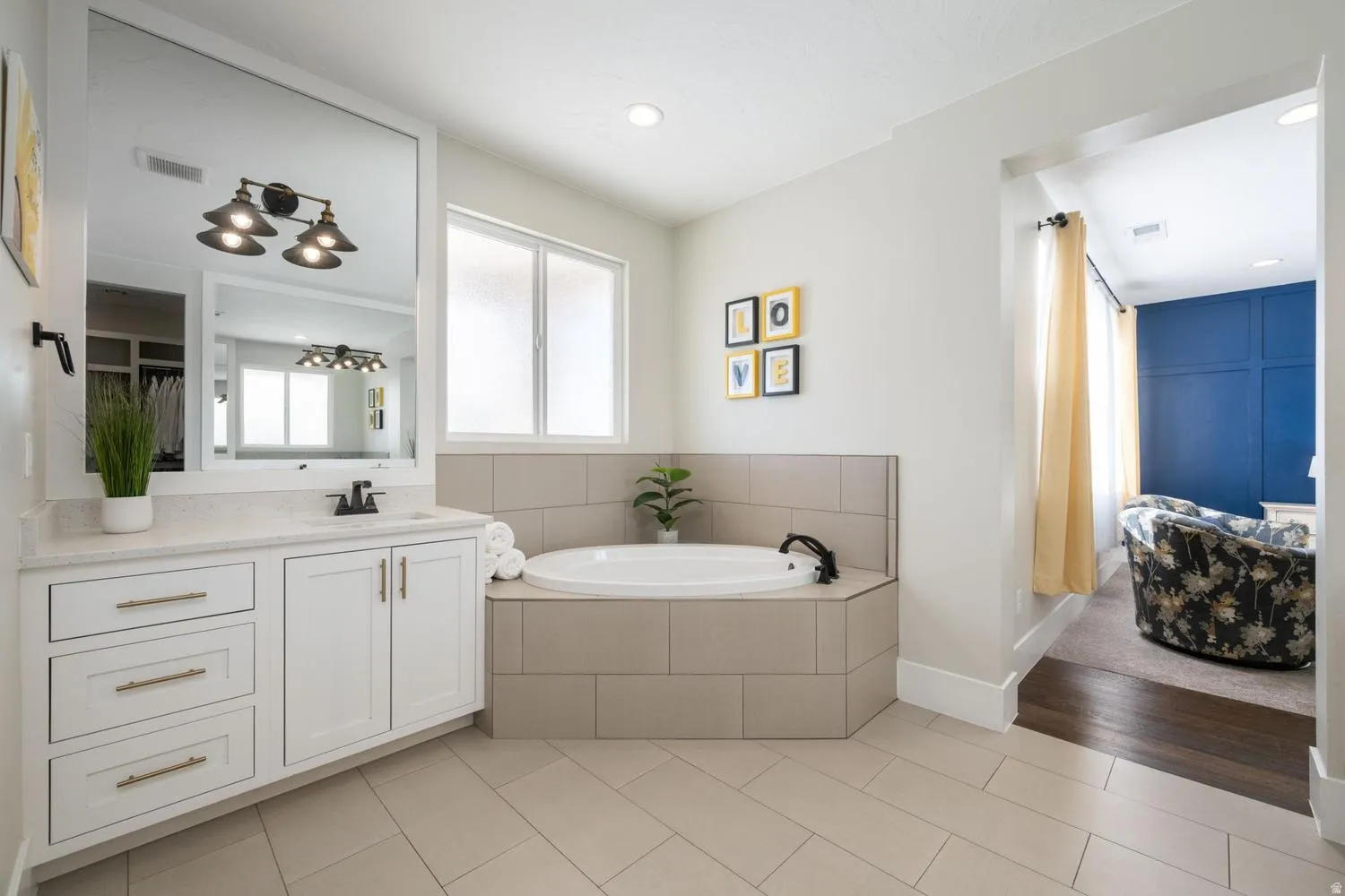 Bathroom featuring a built-in corner soaking tub, white vanity with a light-toned countertop, and tile flooring