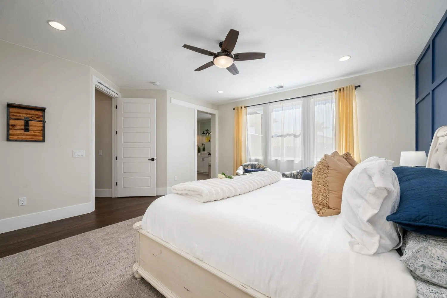 Spacious bedroom featuring dark wood-finish flooring, a contemporary ceiling fan with integrated lighting, and recessed ceiling lights
